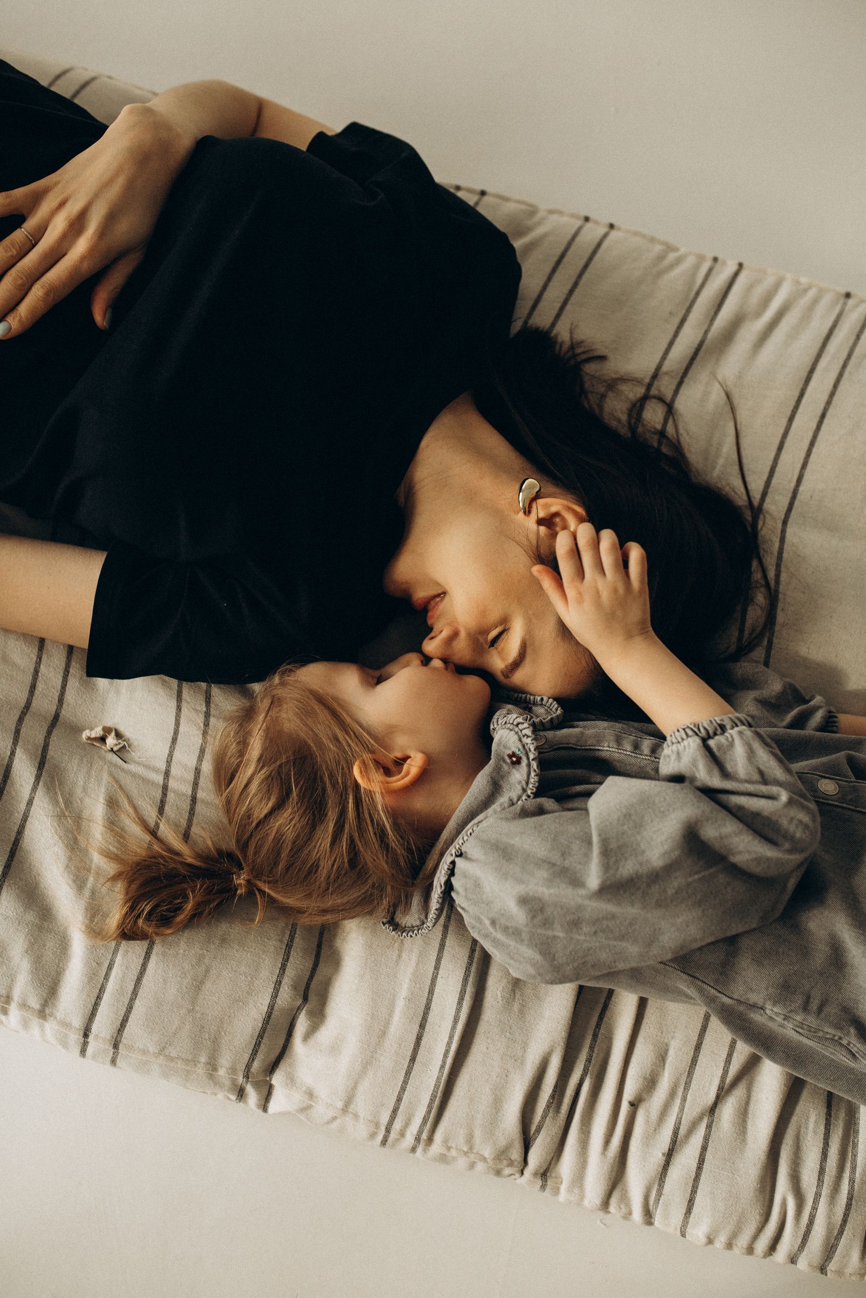 Heartwarming portrait of a mother and daughter lying on a bed, showcasing love and connection.