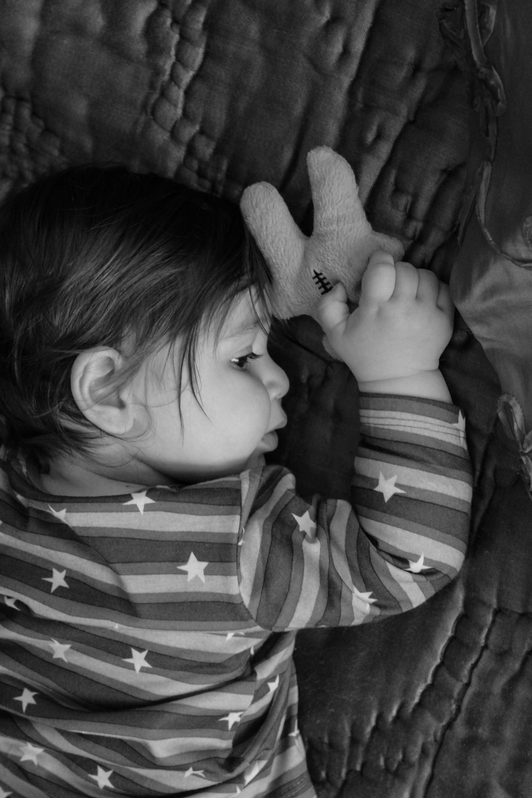 Peaceful sleeping baby holding toy in monochrome, bedtime serenity.
